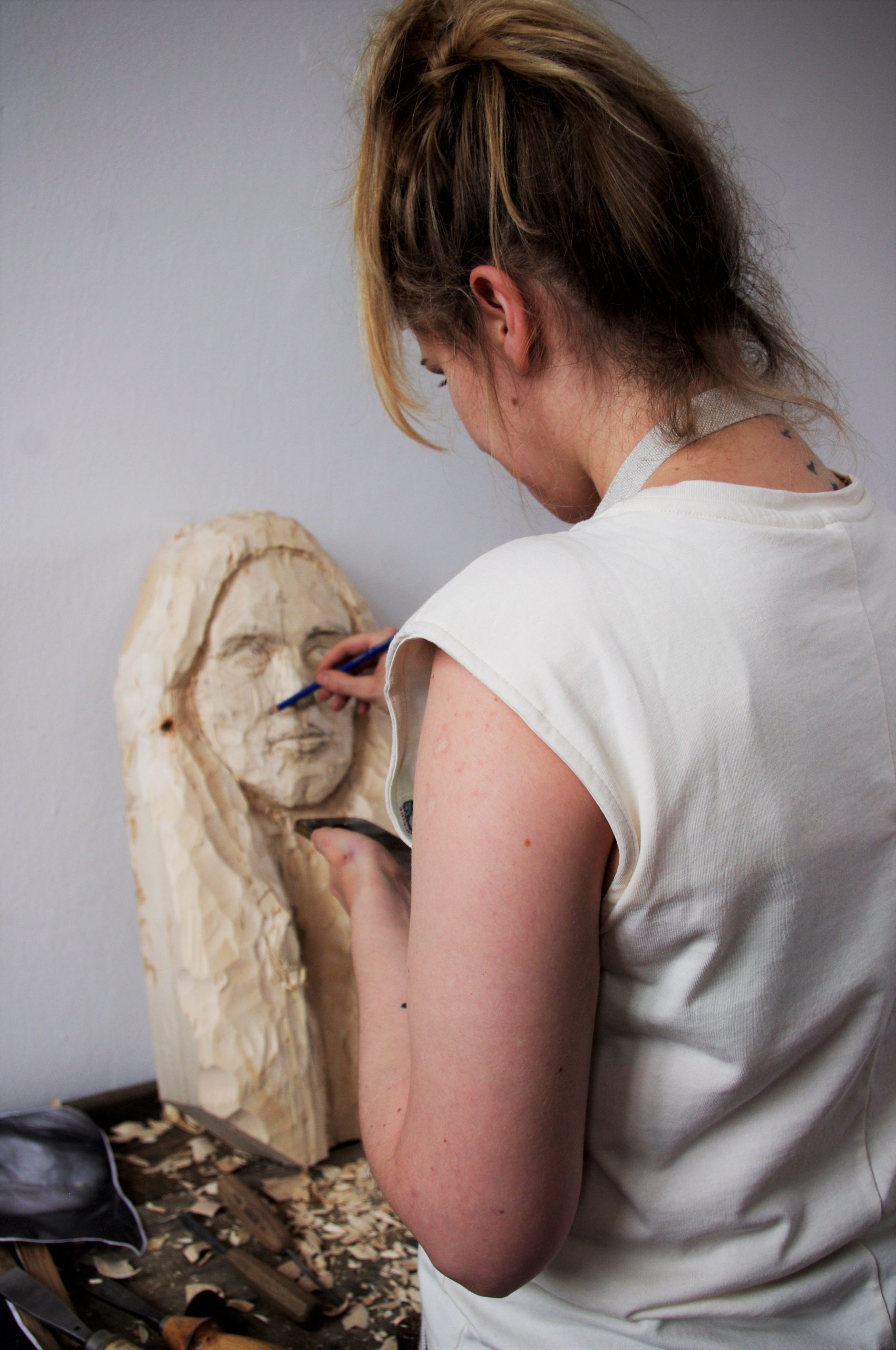 kobieta rzeźbi swój autoportret w drewnie