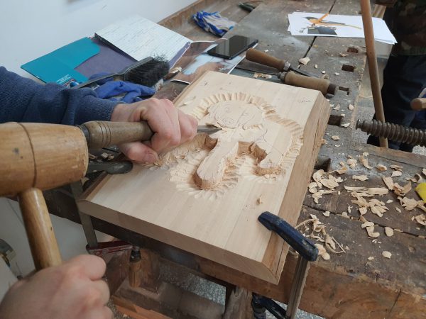 płaskorzeźba pieska w drewnie robiona dłutem
